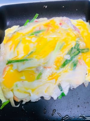 Tuang telur yang sudah dikocok. Setelah permukaannya mengeras, balik dan goreng selama dua menit lagi.

Resep ini menghasilkan dua panekuk seafood dan daun bawang. Gunakan sisa adonan dan bahan-bahan, ikuti langkah-langkah yang sama, untuk membuat panekuk lainnya.

Setelah digoreng, potong kecil-kecil dan nikmati selagi hangat dengan saus yang sudah disiapkan. Segar, harum, dan renyah—satu gigitan saja sudah sangat memuaskan!