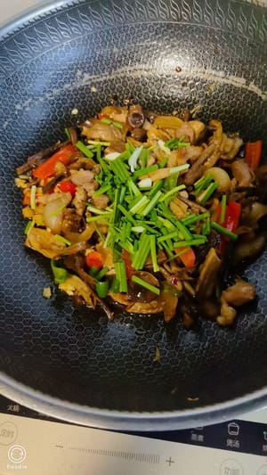 Pour in velvet mushrooms, green and red peppers, stir-fry over high heat for two minutes, then add a spoonful of soy sauce and a little salt for seasoning, stir-fry quickly and evenly. Add scallions before serving.