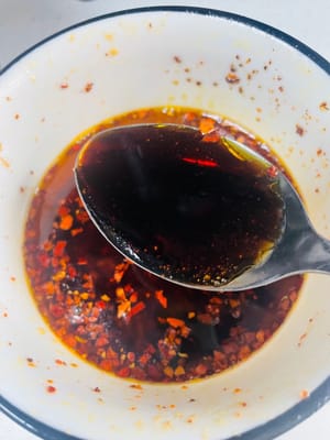 in una ciotola pulita, mettete 2-3 cucchiai di peperoncino in polvere essiccato (o peperoncino tritato, regolate la piccantezza a vostro piacimento) e 3-5 spicchi d'aglio tritato. Scaldate l'olio vegetale a 180-200 °C e versatelo nella ciotola per esaltarne l'aroma. Quindi, aggiungete 3 cucchiai di salsa di soia leggera, 3 cucchiai di aceto invecchiato, 1 cucchiaino di zucchero, 1 cucchiaino di sale e 1 cucchiaino di olio di sesamo. Mescolate bene per creare la salsa.