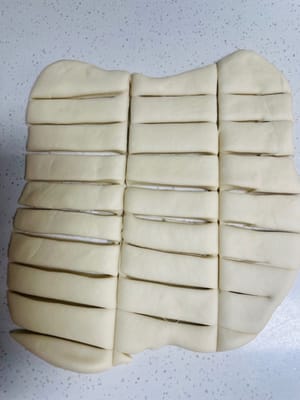 Usa un coltello affilato (come un tagliapasta) per tagliare l'impasto in pezzi di circa 1,5 cm di larghezza e 4 cm di lunghezza (puoi regolare la larghezza a tuo piacimento). Assicurati che i tagli siano netti per creare una base regolare su cui tirare le tagliatelle in seguito.