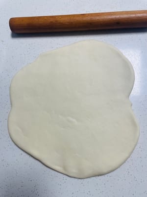 Dopo il terzo impasto e la terza lievitazione, metti l'impasto su un piano di lavoro e stendilo uniformemente con un mattarello (o con un attrezzo professionale per la pasta) fino a formare una frittella di circa 0,5 cm di spessore. Premi uniformemente per evitare disomogeneità di spessore.