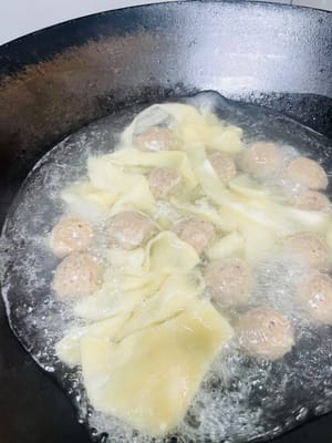 Immergere i noodles tirati in acqua bollente e mescolare subito delicatamente con le bacchette per evitare che si attacchino. Cuocere per 1-2 minuti. (Poiché i noodles variano in spessore e larghezza, osservarli attentamente: sono cotti quando galleggiano e diventano leggermente traslucidi.)
Utilizzare una schiumarola per scolare rapidamente i noodles, scolare l'acqua in eccesso e trasferirli in un piatto preparato.