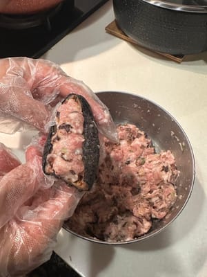 如圖所示，將餡料填入海參中。