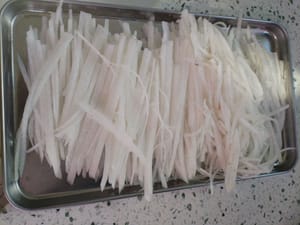 Sbucciare e tagliare a striscioline 500 grammi di ravanello bianco.