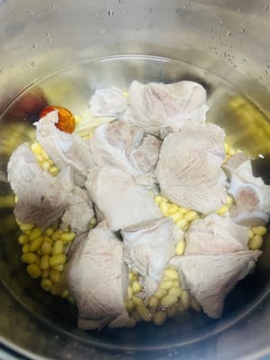 Add ginger slices, candied dates, soybeans, and bones into the pressure cooker. Ginger slices can remove the fishy smell and enhance the flavor, while candied dates can balance the bitterness of bitter melon.