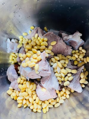 Add ginger slices, candied dates, soybeans, and bones into the pressure cooker. Ginger slices can remove the fishy smell and enhance the flavor, while candied dates can balance the bitterness of bitter melon.