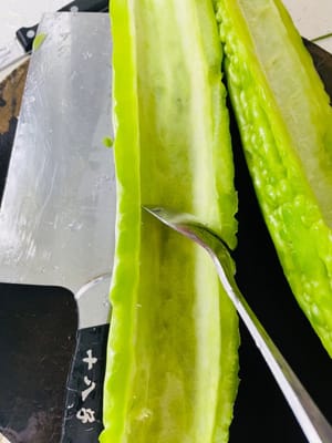 Wash the bitter melon and soak it in clean water for 20 minutes. Cut the bitter melon lengthwise, use a small spoon to scoop out the white pulp and seeds inside, cut it into appropriate pieces and soak it for another 20 minutes.