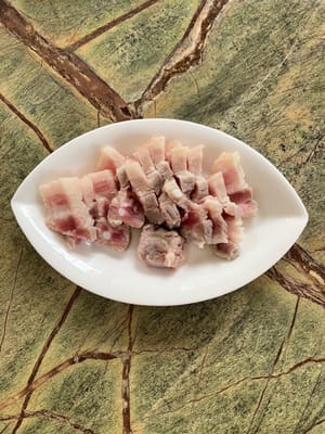 Ponga la carne de cerdo en agua hirviendo durante 2 minutos. Retire la carne, lávela y córtela en trozos.
