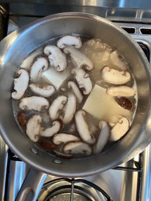 Añade tofu y champiñones a la sopa hirviendo y deja hervir durante 5 minutos más.