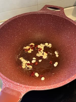 ใส่กระเทียมซอยและพริกแห้งลงไปผัดจนเป็นสีน้ำตาล