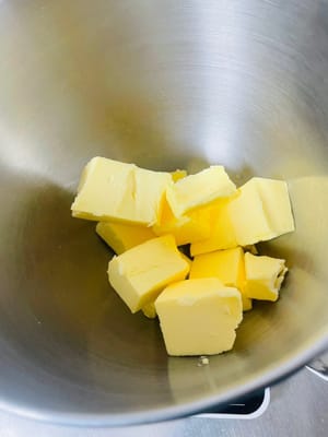 Masukkan mentega lunak ke dalam mangkuk, tambahkan gula halus dan garam, lalu kocok dengan pengocok berkecepatan sedang hingga mentega mengembang dan pucat.