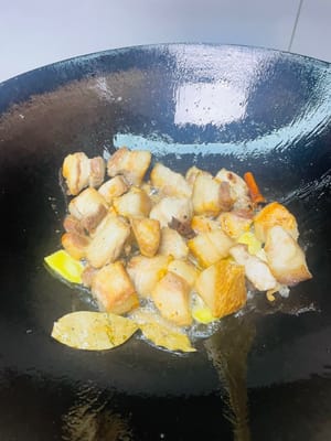 Aggiungere a turno le fette di zenzero, gli spicchi d'aglio, lo zucchero di canna, l'anice stellato, le foglie di alloro e la cannella e soffriggere fino a quando il composto non sarà profumato.