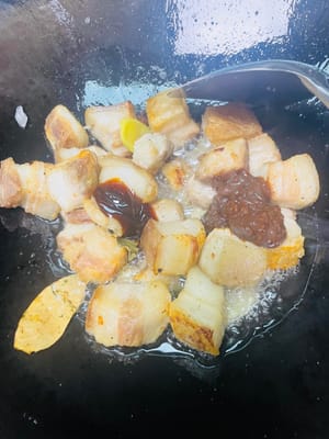 Abbassare la fiamma, aggiungere a turno la pasta di soia, la salsa di soia chiara, la salsa di ostriche e la salsa di soia scura e soffriggere finché non saranno fragranti, quindi aggiungere il vino da cucina e soffriggere. In questo momento la cucina sarà piena di profumo.