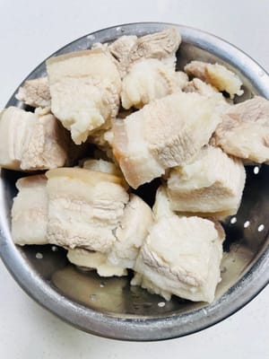 È meglio chiedere al macellaio di arrostire la cotenna del maiale, lavare e asciugare la pancetta, tagliarla a pezzi, metterla in una pentola, aggiungere acqua fredda, grani di pepe di Sichuan, 5 fette di zenzero e vino da cucina. Fate bollire l'acqua per 10 minuti, quindi toglietela dalla pentola, lavatela e mettetela da parte.