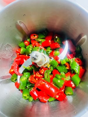Wash the green and red peppers, drain them, pat them dry with kitchen paper, chop them, and then put them into a food processor to grind them.