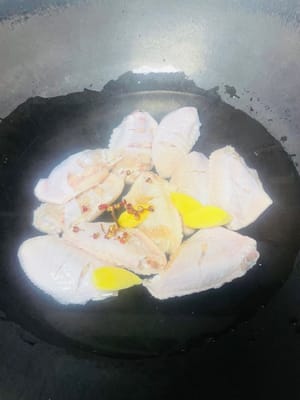 Blanquear las alitas de pollo: Poner agua fría en una olla, añadir las alitas, el vino de cocina, los granos de pimienta de Sichuan (si no hay granos de pimienta de Sichuan, se puede usar cebollino) y rodajas de jengibre, y hervir el agua a fuego alto. Retirar las alitas cuando cambien de color, enjuagarlas con agua limpia para eliminar la espuma y escurrirlas para su uso posterior.