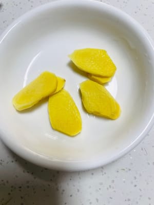 Preparar rodajas de jengibre: Lavar el jengibre, cortarlo en rodajas finas y colocarlo en un recipiente pequeño para usarlo más tarde.