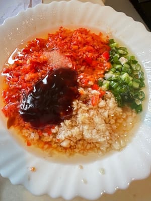 Mezclar todos los condimentos. Los condimentos son los adecuados: salsa de soja, salsa de ostras, ajo, cebollín y sal. Mezclar bien. Verter aceite caliente. Reservar. Dos imágenes.