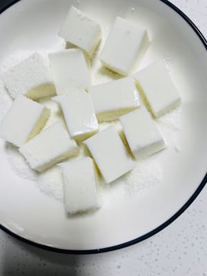 Setelah dikeluarkan dari cetakan, potong menjadi kubus kecil, gulingkan dalam kelapa parut, lapisi setiap sisinya dengan serpihan kelapa. Hidangan penutup kecil ini sangat harum!