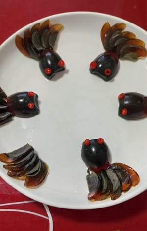 将皮蛋中间切开。一半切薄片摆盘中。另一半做鱼的身体。