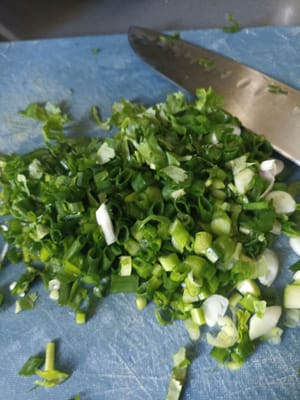 Lavez et nettoyez les oignons nouveaux et les feuilles de coriandre puis hachez-les finement