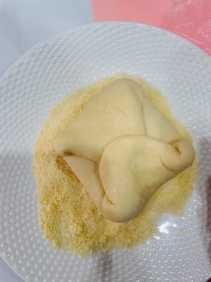 เตรียมจานและเทผงชีสแห้งลงไป ฉีดน้ำเล็กน้อยลงบนผิวหน้าของแป้งที่ห่อไว้ จากนั้นคลึงแป้งในผงชีสให้เคลือบอย่างทั่วถึง