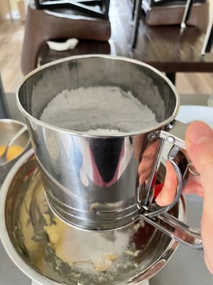 Coloque un plato grande sobre la balanza, tamice el azúcar glas y añádalo, luego controle en la balanza para ver si la cantidad de azúcar glas (50 g) es la correcta.