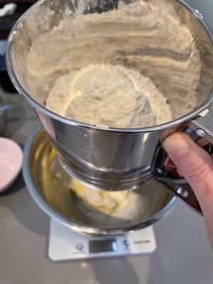 Luego coloque el plato grande sobre la balanza, tamice la harina baja en gluten medida (110 gramos) y agréguela, y verifique si la cantidad de harina en la balanza es correcta.