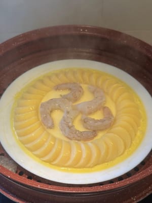 랩을 제거하고 새우를 굳은 달걀 위에 올려놓으세요. 3분 더 쪄주세요.