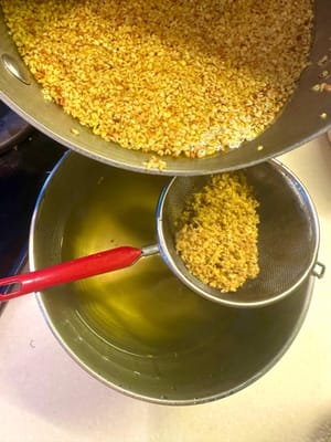 Después, filtra el osmanto y vuelve a verter el agua en la olla. Reserva el osmanto para más tarde.