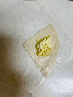 包餡塑形：取一片切好的手抓餅，放上適量榴蓮泥，再撒上一層馬蘇里拉芝士，像包小包袱一樣，把餡料包起嚟（包得醜也沒事，一烤就看不出嚟了～），邊緣仔細捏緊，防止烤的時候露餡 。