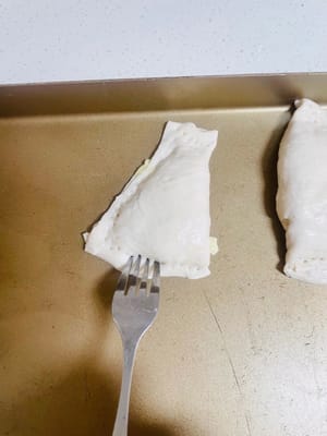 Using a regular fork, poke a few small holes in the corners of the wrapped puff pastry (to help release heat during baking and prevent bulging)