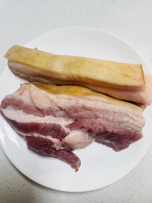 請商家把五花肉皮上的豬毛燒乾淨,拿回家用溫水泡一會兒,再用小刀把皮刮得乾乾淨淨,放旁邊備用。
我特意備了雙倍(500克)的豬肉,不然只切一點嚟炒的話,肥肉佔比就太高了,單炒肥的或單炒瘦的都不好吃,半肥半瘦一起炒又太多。索性煮肉的時候把雙倍量的全煮了,省得下次再煮麻煩,這次炒只挑一部分用,剩下的留著下回做其他菜,超省事。