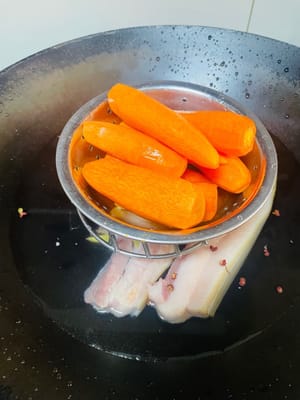 五花肉冷水下鍋,丟點料酒、薑、花椒或青蔥,開火燙水。水開後煮25分鐘,直接把紅蘿蔔也扔進去一起隔水蒸,蒸到用筷子能輕鬆戳透就成,省煤氣又省事兒,主打一個懶人大法。