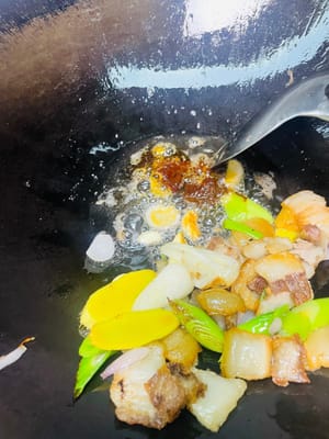 把扒手拉到鍋邊,放入蒜粒、薑片、蒜苗根莖,中小火炒出香味,再挖點紅油豆瓣或乾鍋醬,繼續小火炒出紅油,香得鄰居都嚟敲門。
再把紅蘿蔔片倒進去,和肉、醬料一起翻炒均勻,讓每片紅蘿蔔都裹上醬汁,看著就流口水。