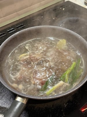 Dans de l'eau froide, ajouter la queue de bœuf, l'oignon vert, le gingembre et le vin de cuisson pour blanchir. Après ébullition, poursuivre la cuisson 5 minutes.