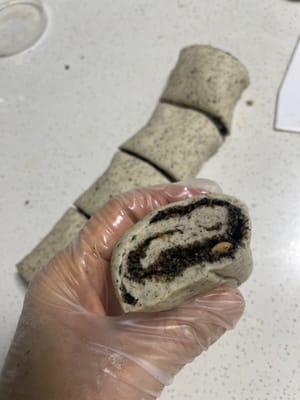 Passaggi per preparare panini al vapore fantasiosi:
1. Prendere l'impasto lievitato e stenderlo in una sfoglia sottile e uniforme, larga circa 20 cm e lunga 30 cm.
2. Distribuire uniformemente il ripieno di sesamo nero sulla sfoglia. Partendo da un'estremità, arrotolare la striscia in una lunga striscia larga circa 2 cm.
3. Tagliare la striscia arrotolata in pezzi di panino al vapore, ciascuno largo circa 3 cm. Lasciare lievitare finché il suo volume non raddoppia, arrivando a 1,5 volte la dimensione originale.