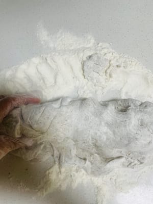 Dopo che l'impasto è lievitato, premetelo delicatamente con un dito inumidito con acqua. Se non torna indietro, è lievitato abbastanza. Quindi, aggiungete la farina e continuate a impastare fino a quando non ci saranno più buchi visibili all'interno dell'impasto quando lo tagliate. Questo è fondamentale per garantire che i panini al vapore o i baozi abbiano una superficie liscia e piana.