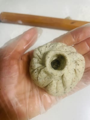 Preparazione dei Baozi:
1. Prendi una palla di impasto da 50 g, appiattiscila con il palmo della mano e arrotolala fino a formare una sfoglia rotonda con un centro spesso e bordi sottili.
2. Disponi una porzione di ripieno al sesamo nero al centro della sfoglia. Richiudi i bordi e stringili bene per evitare che si crepino durante la cottura a vapore.
3. Metti l'impasto avvolto nel cestello per la cottura a vapore e lascialo lievitare finché non raddoppia di volume.