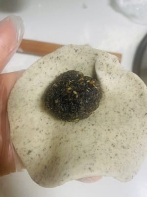 Preparazione dei Baozi:
1. Prendi una palla di impasto da 50 g, appiattiscila con il palmo della mano e arrotolala fino a formare una sfoglia rotonda con un centro spesso e bordi sottili.
2. Disponi una porzione di ripieno al sesamo nero al centro della sfoglia. Richiudi i bordi e stringili bene per evitare che si crepino durante la cottura a vapore.
3. Metti l'impasto avvolto nel cestello per la cottura a vapore e lascialo lievitare finché non raddoppia di volume.