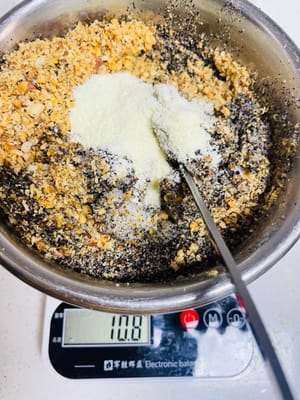 Prendete un contenitore più grande e versateci a turno il sesamo nero in polvere, il latte condensato, il latte in polvere, lo strutto e lo zucchero. Aggiungete quindi le arachidi sbattute, le noci e il liquido delle uova. Mescolate con le mani fino a quando tutti gli ingredienti non saranno completamente amalgamati. Infine, impastate fino a formare delle palline di circa 20 grammi ciascuna e mettetele da parte.