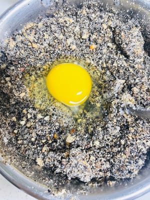 Prendete un contenitore più grande e versateci a turno il sesamo nero in polvere, il latte condensato, il latte in polvere, lo strutto e lo zucchero. Aggiungete quindi le arachidi sbattute, le noci e il liquido delle uova. Mescolate con le mani fino a quando tutti gli ingredienti non saranno completamente amalgamati. Infine, impastate fino a formare delle palline di circa 20 grammi ciascuna e mettetele da parte.
