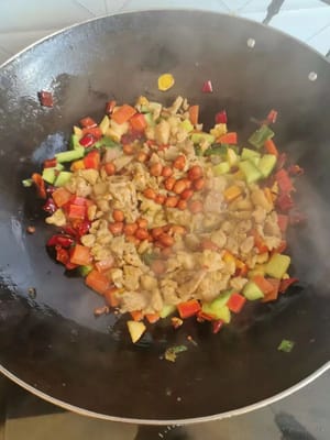 Die zuvor angebratenen, gewürfelten Hähnchenbrustwürfel dazugeben und zum Schluss noch ein paar Erdnüsse hinzufügen.