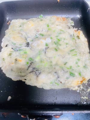 煎制：待油温适宜，倒入一半量的生蚝浆（我煎了2份），转中小火，煎至底部呈现金黄色，进行翻面操作。随后倒入蛋液，继续中小火煎制，期间观察生蚝状态，当生蚝饱满鼓起、两面呈现金黄色（无白色未熟浆粉残留）时，即可装碟，再摆上准备好的香菜。
若偏好口感酥脆的成品，可适当延长煎制时间，但需注意避免生蚝因过度煎制而变干、变老 。