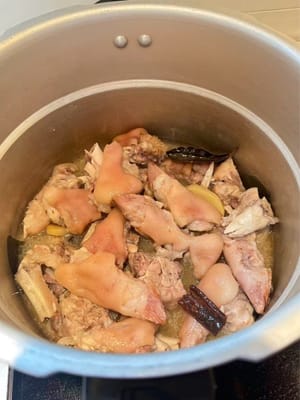 Sobald die Schweinshaxen gar geschmort sind, aus der Gewürzmischung nehmen und auf einem Teller anrichten.