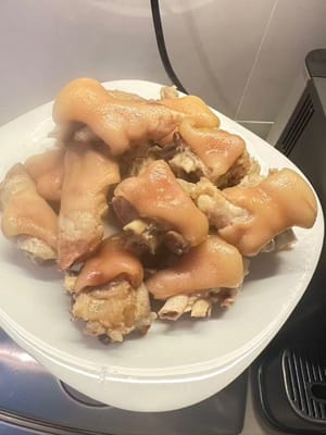 Sobald die Schweinshaxen gar geschmort sind, aus der Gewürzmischung nehmen und auf einem Teller anrichten.