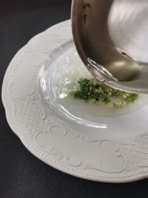 Préparez les oignons nouveaux émincés et l'ail haché dans une assiette, puis versez dessus l'huile chaude.