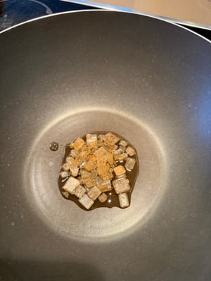 Add 50g of rock sugar and two tablespoons of oil to an empty pan, turn on medium heat, and gently tap the rock sugar with the back of a spatula.