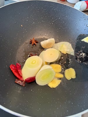Heat oil, then add scallions, dried chili peppers, ginger, cinnamon, and star anise.
