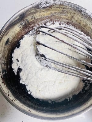 Sift in the cake flour: Sift 70g of cake flour into the chocolate mixture. Stir gently in an N-shaped pattern to ensure that the flour and liquid are fully combined to form a uniform egg yolk paste. Set aside.